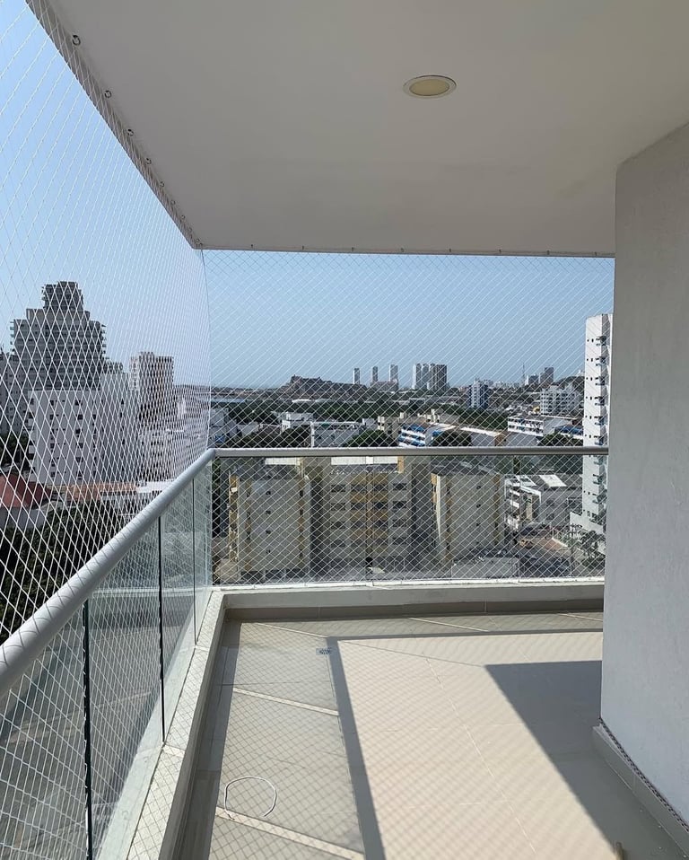 High-rise balcony with safety netting overlooking urban cityscape with multiple buildings and streets