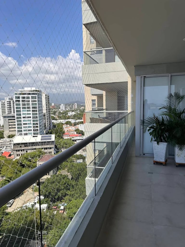 High-rise apartment balcony with safety netting overlooking urban cityscape and residential buildings