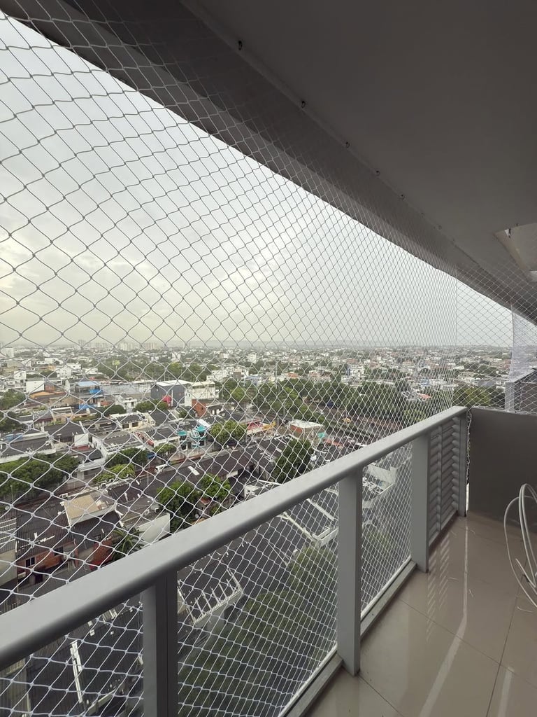 High-rise balcony with safety netting overlooking an urban cityscape with buildings and trees on a hazy day