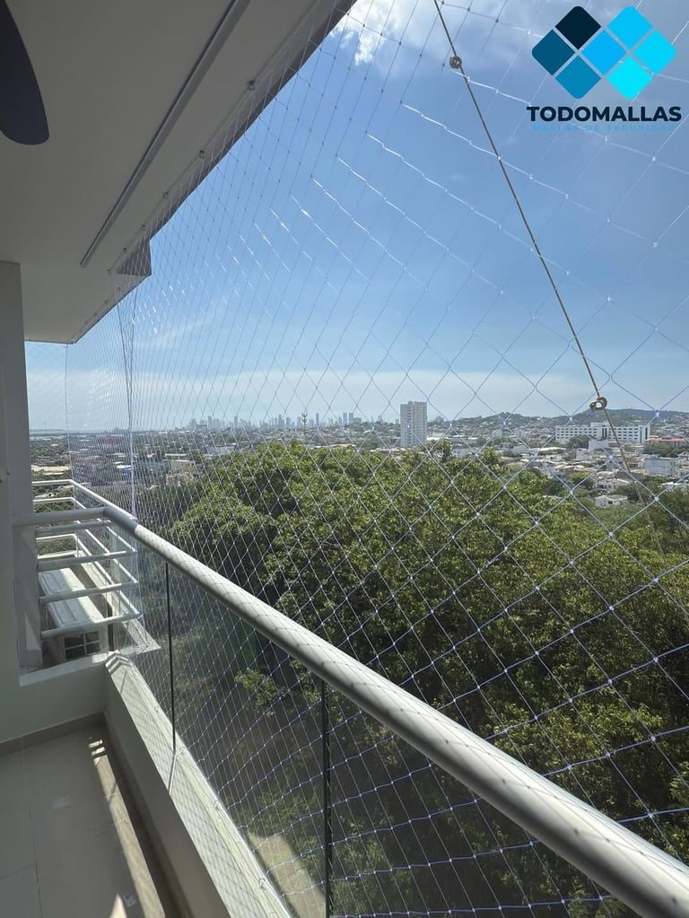 High-rise balcony with protective safety netting overlooking a cityscape with trees and distant buildings under blue sky